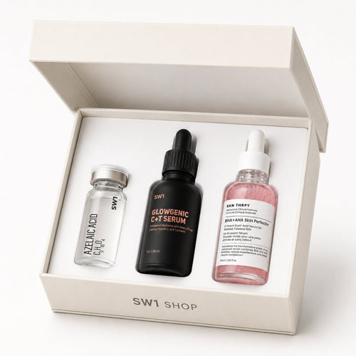 June Glow-Up Kit cream gift box open showing three serum bottles: AZELAIC ACID ampoule, GLOWGENIC C+T Serum matte black bottle, and BHA+AHA Skin Perfector pink serum, with SW1 SHOP wordmark on the box front. SW1 Shop, Singapore.